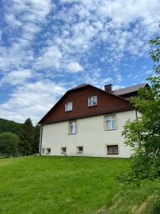 a large white house with a brown roof on a green field at Cicha Dolina in Cisna