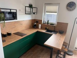 a kitchen with green cabinets and a wooden counter top at Słoneczne Apartamenty in Ustronie Morskie