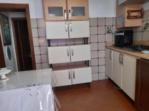 a kitchen with white cabinets and a tile wall at Il Casale degli Artisti in Ravigliano