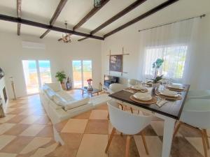 Villa del Sol في بينالمادينا: غرفة طعام وغرفة معيشة مع طاولة وكراسي