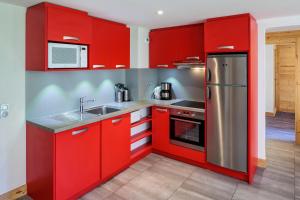 a kitchen with red cabinets and a stainless steel refrigerator at Noemys Backgammon in La Plagne