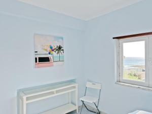um quarto branco com uma janela e uma cadeira em Go surf em Parede