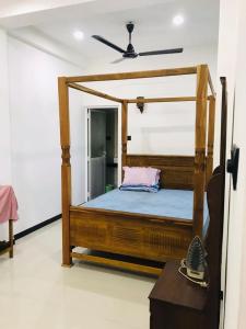 1 dormitorio con cama de madera con dosel y almohada rosa en Roshan Villa en Weligama