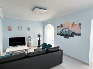 ein Wohnzimmer mit einem schwarzen Sofa und einem TV in der Unterkunft Go surf in Parede