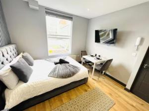 a bedroom with a bed and a table and a television at Studios next to Emirates Stadium in London
