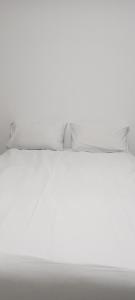 a white bed with two pillows on top of it at Esteem Guesthouse in Okakarara