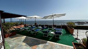 una piscina con sedie, ombrelloni e oceano di Hotel Centro Congressi Polo Nautico a Salerno