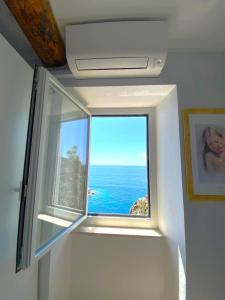 a window in a room with a view of the ocean at Apartment La Scogliera - Riomaggiore in Riomaggiore