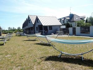 a house with two hammocks in front of a yard at Holiday Home in Dziwnówek by Sea and Lake in Dziwnówek