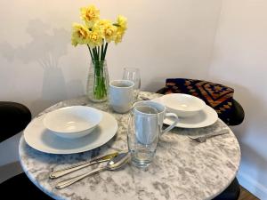 a table with plates and cups and a vase of flowers at Delightful 1 bed, 1 bath Norfolk Broads Guesthouse in Halvergate