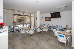 un comedor con mesas, sillas y ventanas en Hostal El Mercat, en Villajoyosa