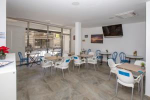 a dining room with tables and chairs and windows at Hostal El Mercat in Villajoyosa