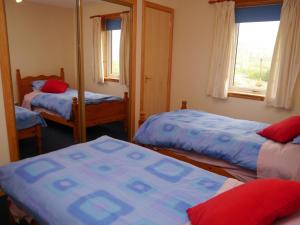 a bedroom with three beds and a mirror at Loneacre in Wick