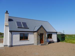 a small white house with solar panels on it at Loneacre in Wick