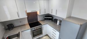 uma pequena cozinha com armários e electrodomésticos brancos em ExCel Exhibition Center Apartment em Londres