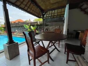 uma sala de jantar com mesa e cadeiras e uma piscina em Kasapa Inn em Ubud