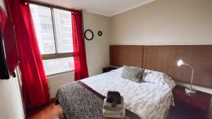 1 dormitorio con 1 cama y una ventana con cortinas rojas en Apartamentos Bulnes en Santiago