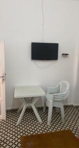 a white table and a chair and a tv on a wall at Inviting 1-Bed Apartment in Ksar sghir in Ksar es Sghir