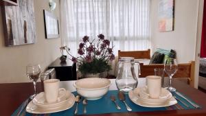 a table with a bowl and plates and wine glasses at Apartamentos Bulnes in Santiago