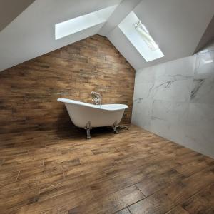 a bathroom with a white bath tub and wooden floors at Green Hill House 