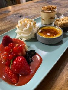 a plate of food with strawberries and whipped cream and a dessert at Hôtel Génépi in Beuil