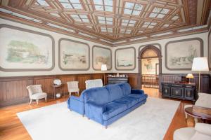 ein Wohnzimmer mit einem blauen Sofa und Fenstern in der Unterkunft Palace Museum - Espaço Palmeiras in Porto