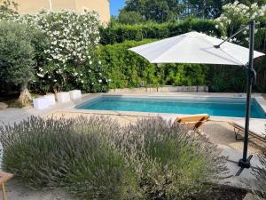 un ombrellone bianco accanto a una piscina di Villa Aprile a Saint-Étienne-du-Grès
