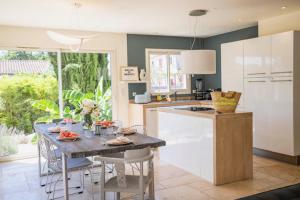 una cucina con un tavolo con sedie e un piano di lavoro di Villa Aprile a Saint-Étienne-du-Grès