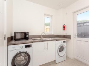 a kitchen with a washing machine and a microwave at The Beech House in Aviemore