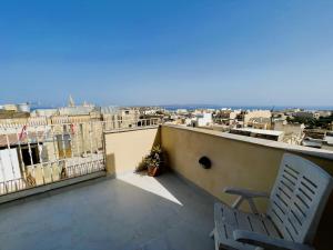 a balcony with a chair and a view of a city at All Nations Holiday Home in Għajnsielem