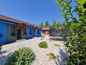 a garden with a blue house with a bench at Apartmány Betica in Nesvady