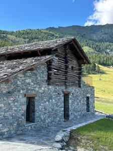 an old stone building with a mountain in the background at Raccard Resort de Montagne in Torgnon