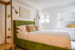 a bed with a green headboard in a bedroom at Luxe Contemporary Cotswold Pad - Heart of Stow in Stow on the Wold