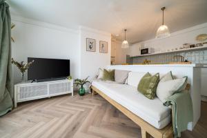 uma sala de estar com um sofá branco e uma televisão em Luxe Contemporary Cotswold Pad - Heart of Stow em Stow on the Wold