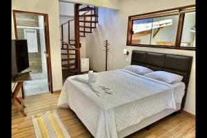 a bedroom with a bed with white sheets and a television at OYO Deck Da Villa Pousada Hotel in Picinguaba