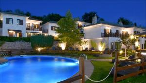 a villa with a swimming pool in front of a house at Hotel Pelion Resort in Portaria