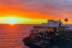 a house on a cliff with the sunset in the background at Hotel Nettuno in Ischia