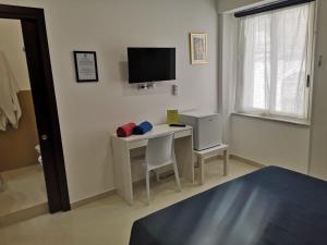 een kamer met een bureau, een televisie en een bed bij Tulla's in Giardini Naxos