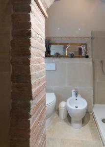 a bathroom with a brick wall and a toilet and a sink at La Casa Rossa in Coiano +23 photos