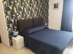 Un dormitorio con una cama azul y una pared estampada en Tulla's, en Giardini Naxos