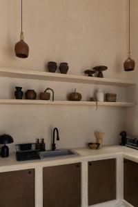 a kitchen with a sink and shelves with pottery at Narrativ Lofts - Lira - Mid Century Cozy Retreat in Campeche