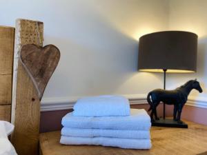 a pile of towels on a table with a lamp and a horse statue at Stunning quirky home in Amble in Amble