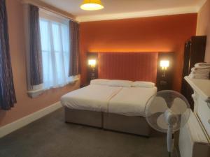 Habitación de hotel con cama y ventilador en Acacia Hotel, en Londres