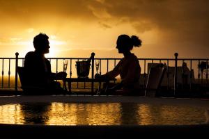Due persone sedute a un tavolo accanto a una piscina di Hotel Nettuno a Ischia