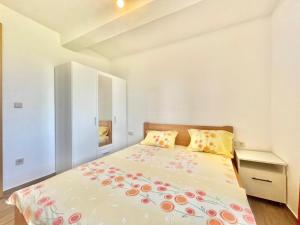 ein weißes Schlafzimmer mit einem Bett mit Blumen darauf in der Unterkunft Talia Apartments in Budva