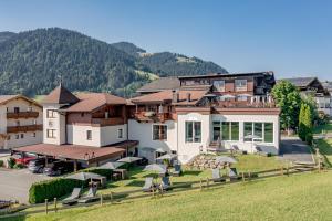 a large house with a mountain in the background at DER GREIL - Wein & Gourmethotel in Söll