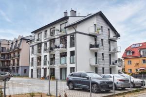 un edificio blanco con coches estacionados frente a él en Rafiki en Międzywodzie