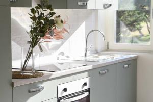 a white kitchen with a sink and a vase of flowers at Roma Aurelio appartamento con piscina in Rome