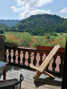 una silla de madera en una terraza con flores en Gasthaus - Pension - Café Dörfl en Kiefersfelden