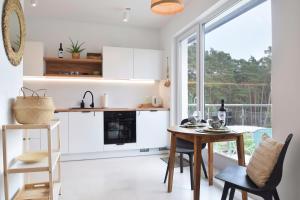 a kitchen with white cabinets and a table and chairs at Rafiki in Międzywodzie